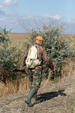 A hunter with a gun in camouflage clothing. A gentleman with a gun, medium shot, unrecognizable.