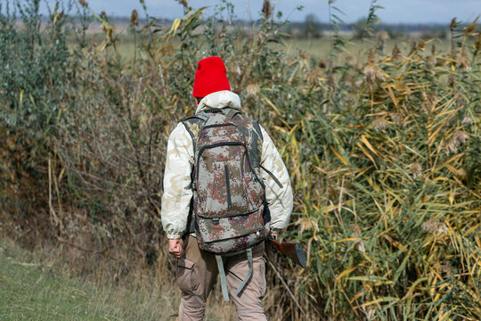 A hunter with a gun in camouflage clothing. A gentleman with a gun, medium shot, unrecognizable.