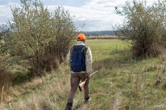 A hunter with a gun in camouflage clothing. A gentleman with a gun, medium shot, unrecognizable.