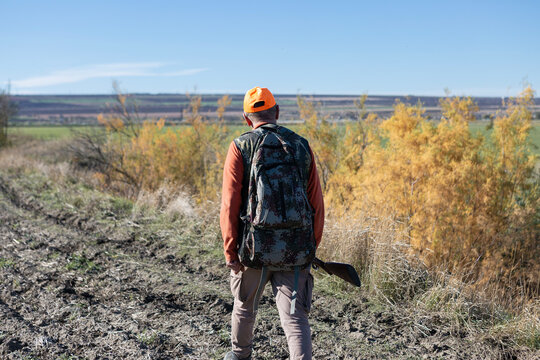 A hunter with a gun in camouflage clothing. A gentleman with a gun, medium shot, unrecognizable.
