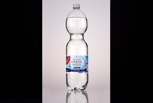 Front view of a Gut & G&uuml;nstig Classic 1.5 litre sparkling mineral water bottle with an EDEKA-branded blue-and-white German label and white screw cap. Backlit studio photograph on a reflective surface 