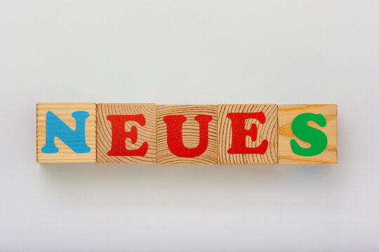 he image features wooden blocks with the German word NEUES meaning new in English displayed in colorful letters
