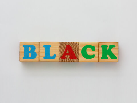 Wooden blocks spelling the word BLACK feature colorful letters blue, red, green