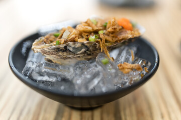 Fresh raw oysters that topping with spicy seafood sauce and other ingredient, served on iced. Thai food menu. © Dontree