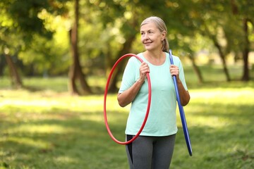 Senior woman with hula hoops in park, space for text © New Africa