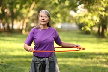 Senior woman exercising with hula hoop outdoors © New Africa