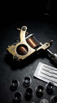 Vintage Tattoo Machine and Supplies on Dark Surface.