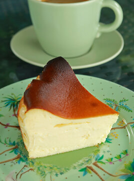 Slice of mouth watering Basque burnt cheesecake with perfectly caramelized top on a ceramic plate
