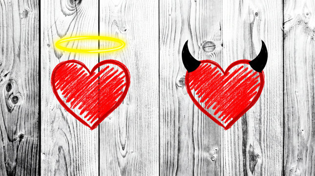 A conceptual image of two red scribbled hearts on a white wooden background, one with a yellow halo and the other with black devil horns representing duality.