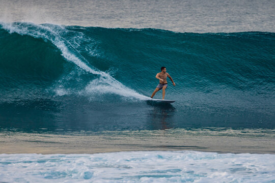 Surfer on a powerful ocean wave, carving across the water with white spray