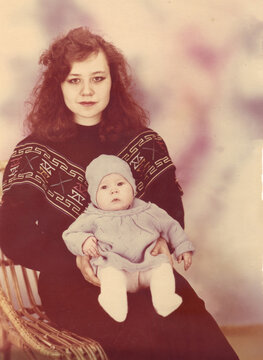 A young mother holds her infant in a 1990s studio portrait