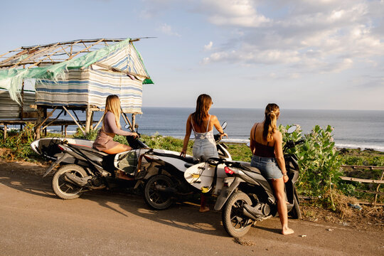 Three surfers checking the ocean from their scooters in Indonesia