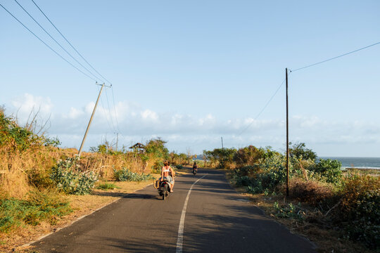 Friends riding scooters on a remote coastal road
