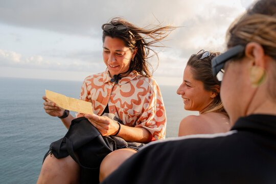 Friends reading birthday gift note by the ocean in Indonesia