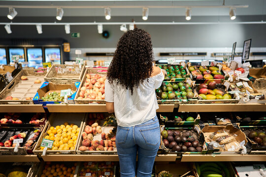 Woman shopping for fresh produce in supermarket aisle