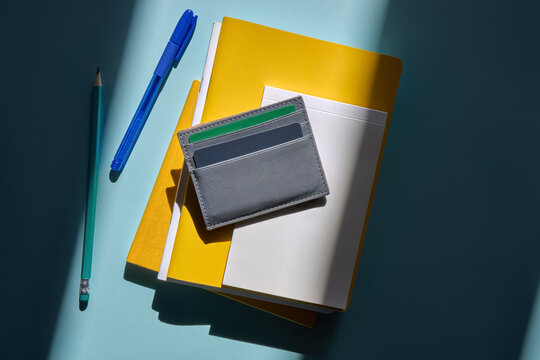 Gray Card Holder With Yellow Notebooks And Pens On a Blue Desk
