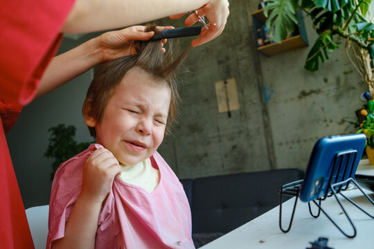 Little boy crying and making a face during a home haircut.