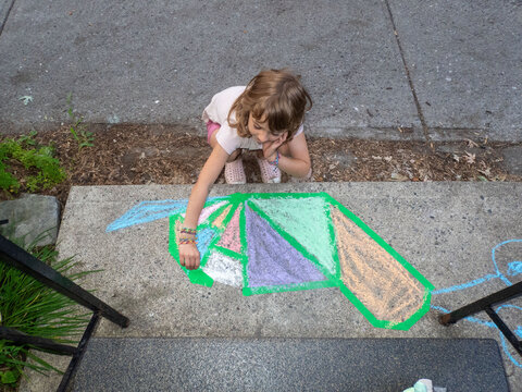 Child drawing colorful chalk art on the front step