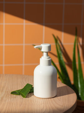 White pump bottle with aloe vera slices on a wooden surface