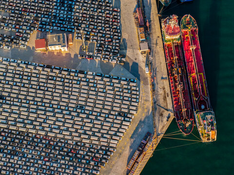 Cargo ships and rows of new cars at port