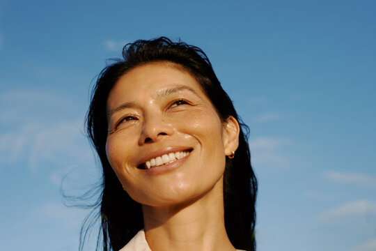 Woman Smiles Against a Clear Blue Sky During Daytime