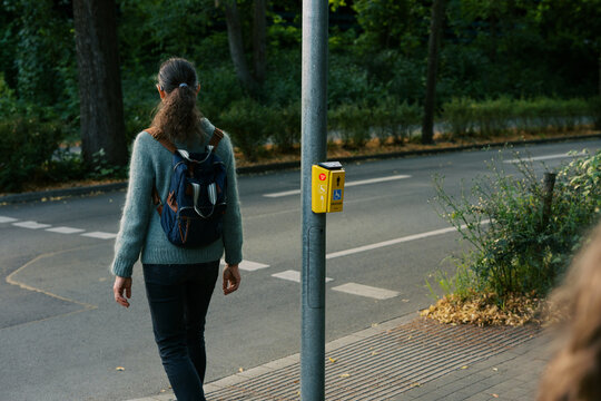 woman with backpack waiting at crosswalk in germany