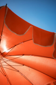 Bright Orange Beach Umbrella Against Blue Sky