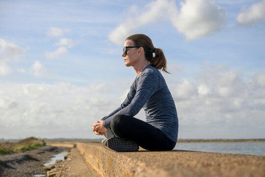 Woman Sitting Meditating on a Coastal Seawall