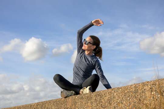 Woman Sitting on Wall doing Arm Stretching Warm Up Exercises