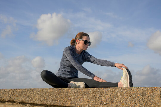 Woman doing a Leg Stretch Warm Up Exercise on a Stone Wall