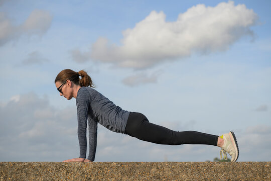 Woman Performing Plank Exercise on Stone Wall