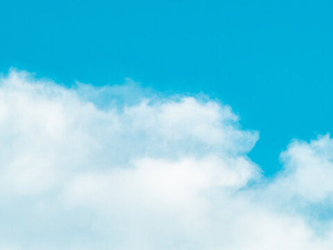 Vertical soft white clouds drifting across a vivid blue sky, airy cloudscape background with gentle wispy texture and copy space