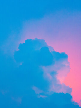 Blue cumulus cloud against a vivid pink and purple sunset sky, dreamy surreal pastel gradient cloudscape with soft glowing light