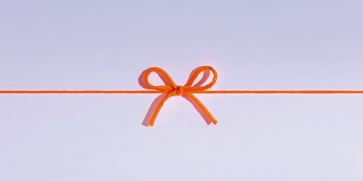 String tied in a bow on a horizontal orange paper cord, featuring a crinkled fiber texture for eco packaging and gift wrap design