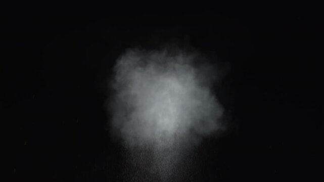 Dusty bullet impact against a wall, sending fragments of debris flying through the air. White powder burst isolated on black background. Explosive hit, scattering dust particles. Cloud of fine debris
