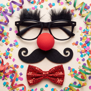 A whimsical clown face composition created with black glasses, a red foam nose, a black mustache, a sequined bow tie, and colorful party confetti.