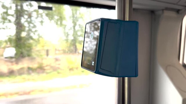 A hand holds a transit pass up to a validator on public transport