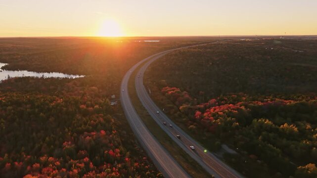 Golden autumn light follows a highway through the woodlands of nova scotia, canada