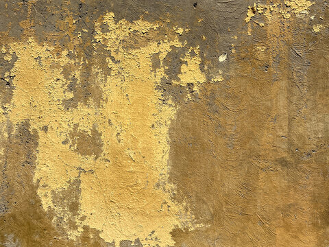 Peeling yellow paint revealing a weathered dark brown stucco wall surface, creating an abstract background texture with rough details and distressed elements in Calle Duquesa, Granada