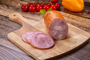Charcuterie platter with smoked ham sausage, sliced meat, cherry tomatoes and yellow bell pepper on wooden board, cold cut appetizer © Andrei Starostin