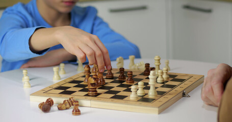 Close up of chess pieces on board. Defocused players play chess game at home. Wooden figures in chess game match. Strategy and intelligence concept video. © julia_diak