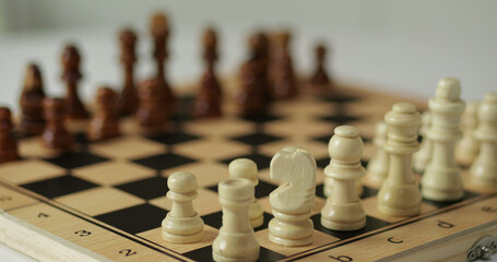Hand moves chess piece on wooden board during focused play. Chess moment shows decision making and control. Chess strategy reflects thinking process. Close view of chess supports leadership, planning © julia_diak