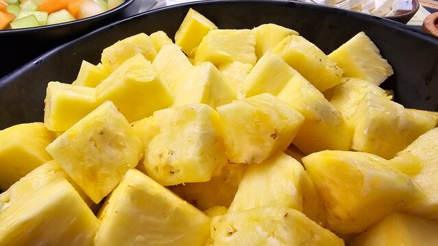 Chopped pineapple chunks inside a black bowl in a restaurant restaurant