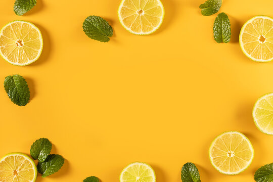 Citrus fruit slices and mint leaves framing yellow background
