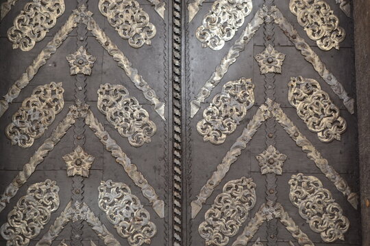 Ornate metal door with silver ornaments and embossed panels for architectural detail background and historic entrance design