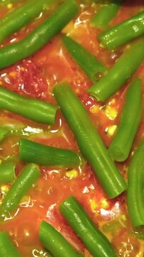 Preparation of Green bean dish. Hot Yardlong beans cooking in a pan with tomatoes, olive oil, herbs spices. French piattoni beans. Stir-fry kidney beans. Homemade Sauteed Cooked Edamame, soy. Haricots