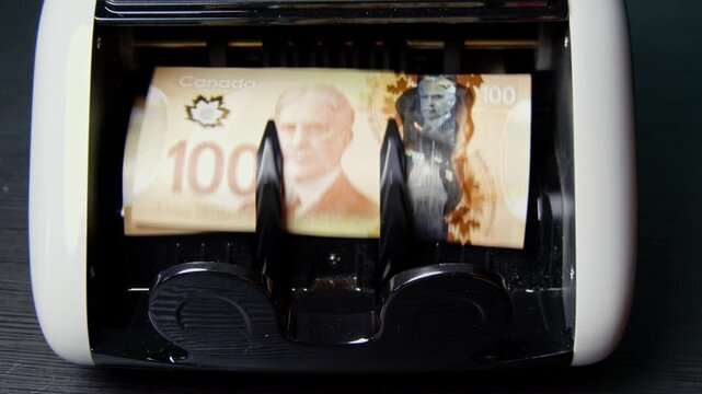 A currency counting machine quickly processes a thick stack of banknotes, accurately counting and organizing the notes into a neat, orderly bundle