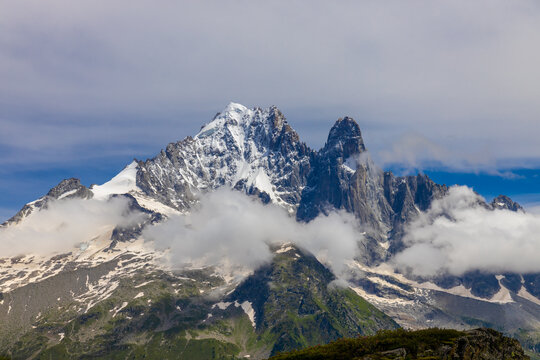 Impressive view of Les Drus, a dramatic pair of granite peaks in the Mont Blanc massif of the French Alps near Chamonix. The iconic mountain formation rises above deep alpine valleys