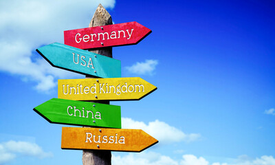 Germany, USA, United Kingdom, China, Russia - wooden signpost with five arrows, sky with clouds © PX Media