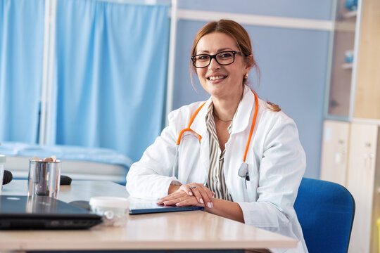 An female doctor stands in her medical office, looking professional and confident. The portrait reflects her experience and dedication to caring for patients.